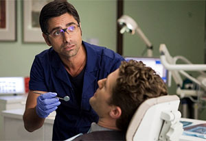 This won&#8217;t hurt a bit, Mr. Schuester. Actually, it might — a lot. But it&#8217;s Will&#8217;s heart, not his teeth, that is most in jeopardy when John Stamos joins Glee in Season 2&#8217;s second episode as Emma&#8217;s dentist beau, Dr. Carl Howell.&#8220;Just when Will thinks he&#8217;ll win Emma because he can sing and dance, we find out Carl used to be in an &#8217;80s boy band,&#8221; reveals John, who&#8217;ll likely sport a mullet for flashbacks. &#8220;I discover Will&#8217;s chewing his teeth, so the other day I had, like, four fingers in Matthew Morrison&#8217;s mouth.&#8221;Carl will also be administering anesthesia to hygienically challenged students Rachel, Artie, Brittany and Santana, inspiring a dreamy sequence that will take them into the world of Britney Spears. &#8220;Poor Brittany has cavities in every tooth,&#8221; says John, who will also appear in the Rocky Horror Picture Show — themed Halloween episode. &#8220;I can&#8217;t tell you what character I&#8217;m playing, but I will be singing,&#8221; he promises. Talk about doing the &#8220;Time Warp!&#8221;  tvguide
