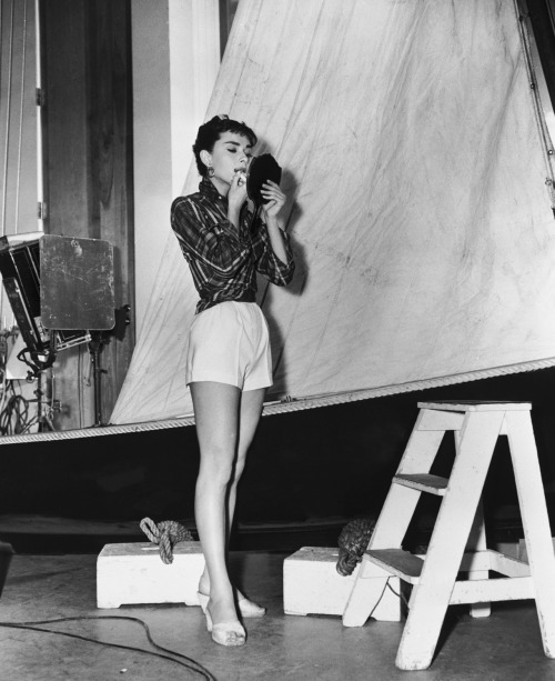 theniftyfifties:

Audrey Hepburn applies lipstick on the set of ‘Sabrina’, 1954.
